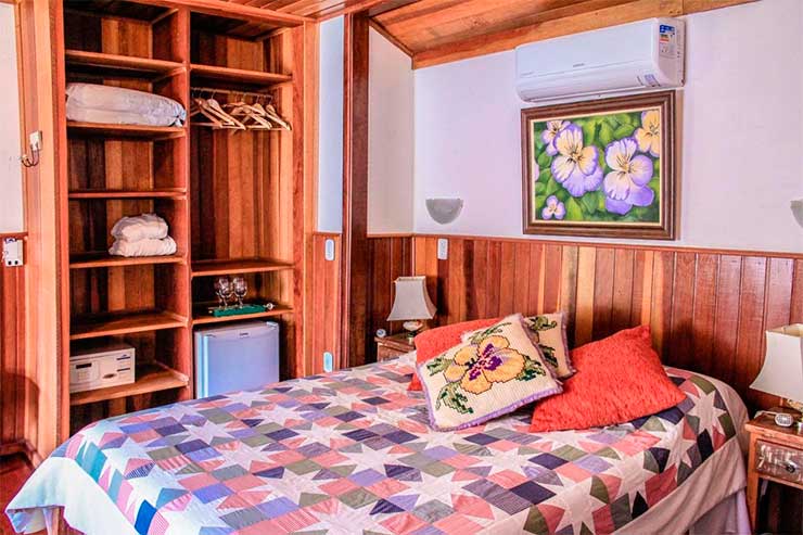Pousadas em Visconde de Mauá: Quarto da Vale das Hortênsias com cama de casal e tons de madeira