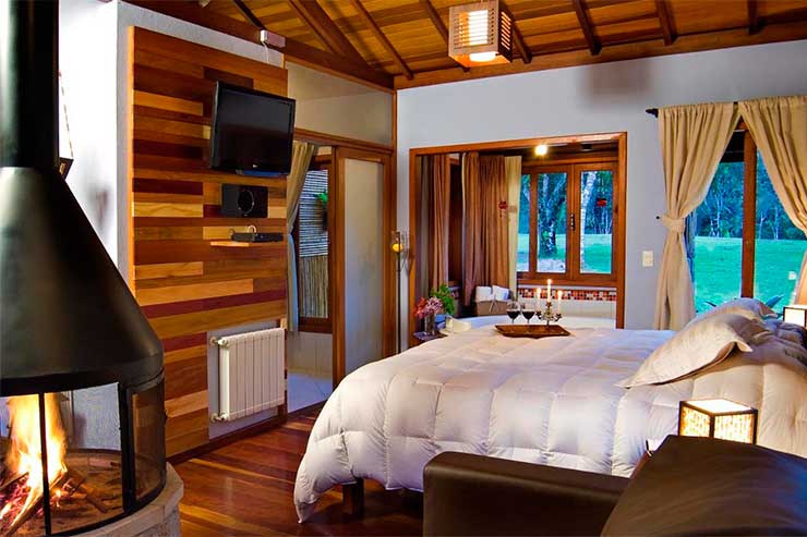 Pousadas em Visconde de Mauá: Quarto da Villa Acauã com lareira em tons de madeira