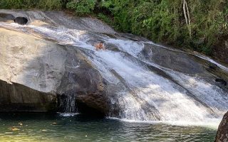 Homem escorregando na Cachoeira do Escorrega em Visconde de Mauá