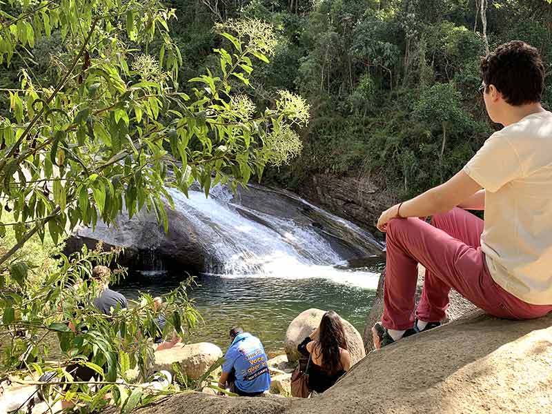 Adolfo sentado em pedra com vista pra Escorrega em Visconde de Mauá