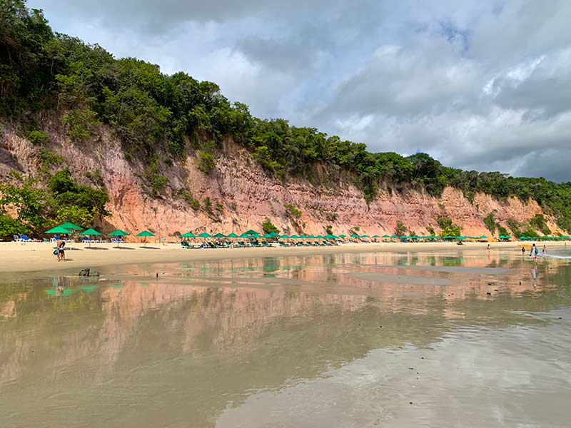 Areia, falésias, mar e espreguiçadeiras na Baía dos Golfinhos, uma das melhores praias de Pipa
