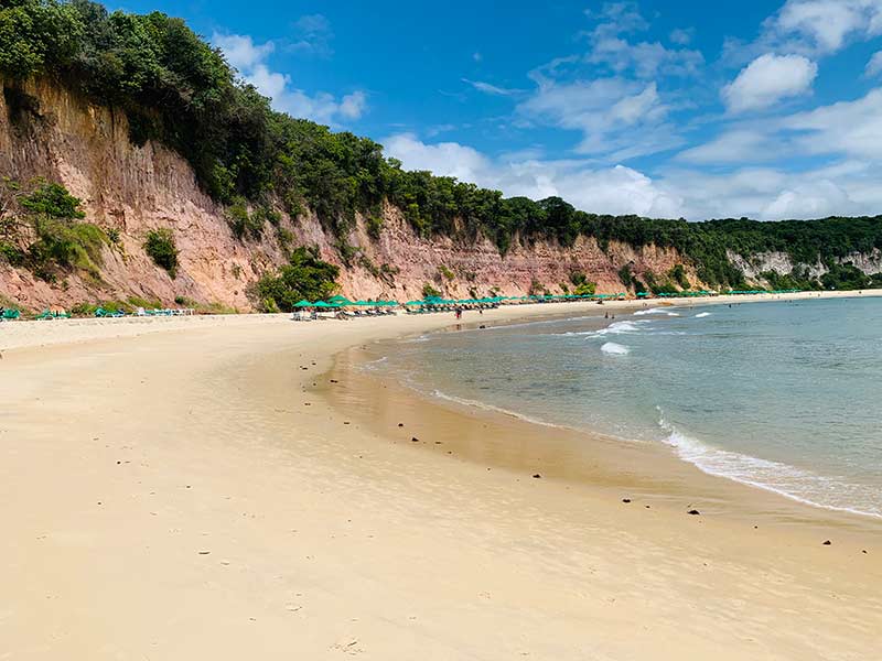 Barracas de praia na areia, falésias e mar na Baía dos Golfinhos, uma das melhores praias de Pipa
