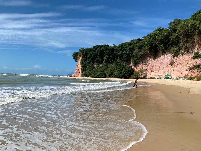 Homem sai do mar rumo à areia na Baía dos Golfinhos