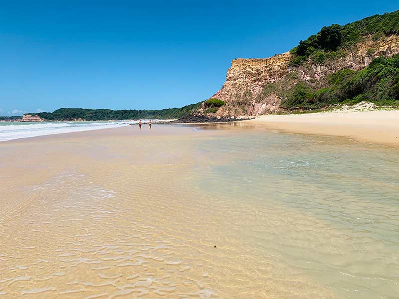 Pessoas caminham no mar calmo de Cacimbinhas, no RN