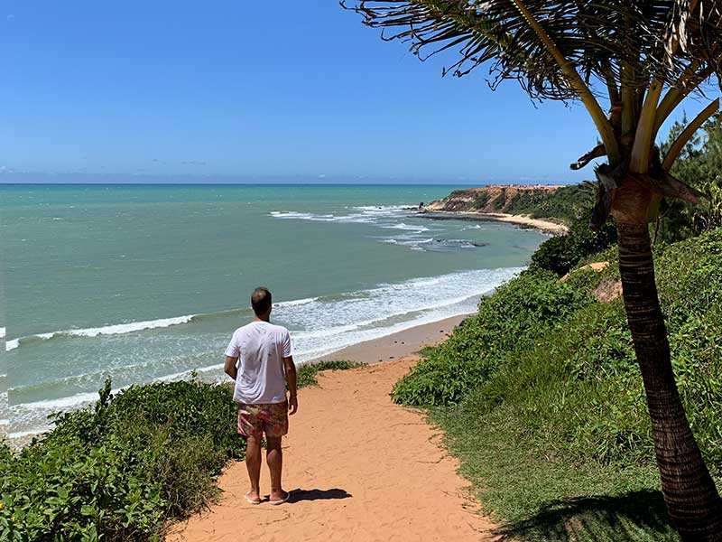 Homem em pé no alto da falésia na Praia do Amor