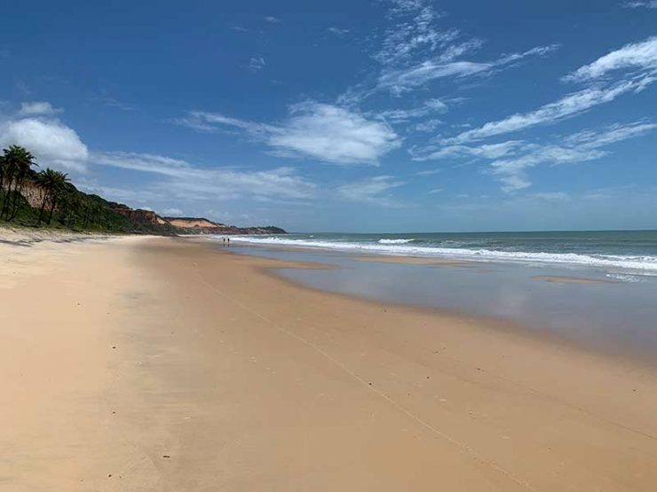 Extensa faixa de areia vazia em dia de céu azul