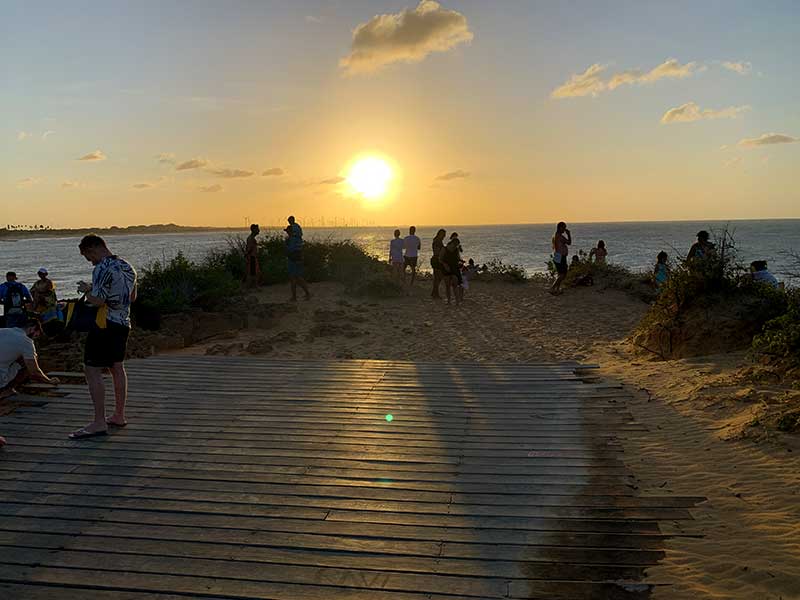 Pessoas em plataforma nas dunas assistem ao pôr do sol na Praia de Tourinhos