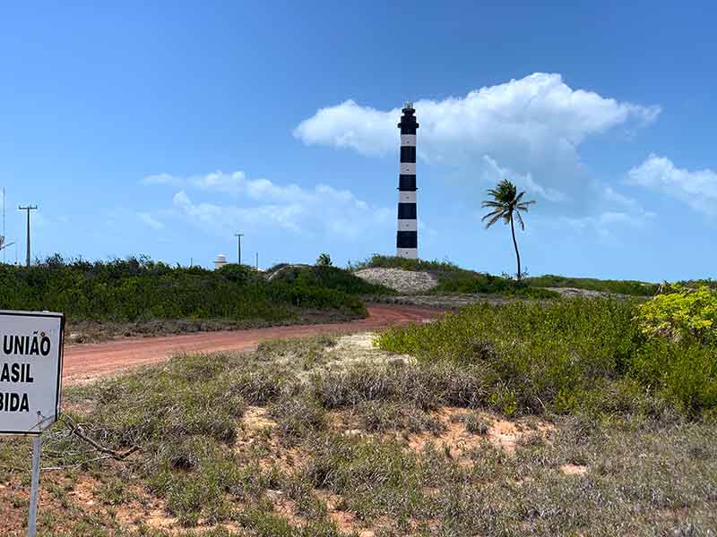 Farol do Calcanhar em área fechada perto de plantações em dia de céu azul