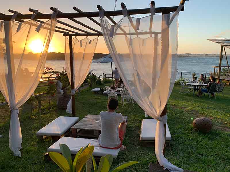 Homem vê o pôr do sol na Lagoa Guaraíras em lounge