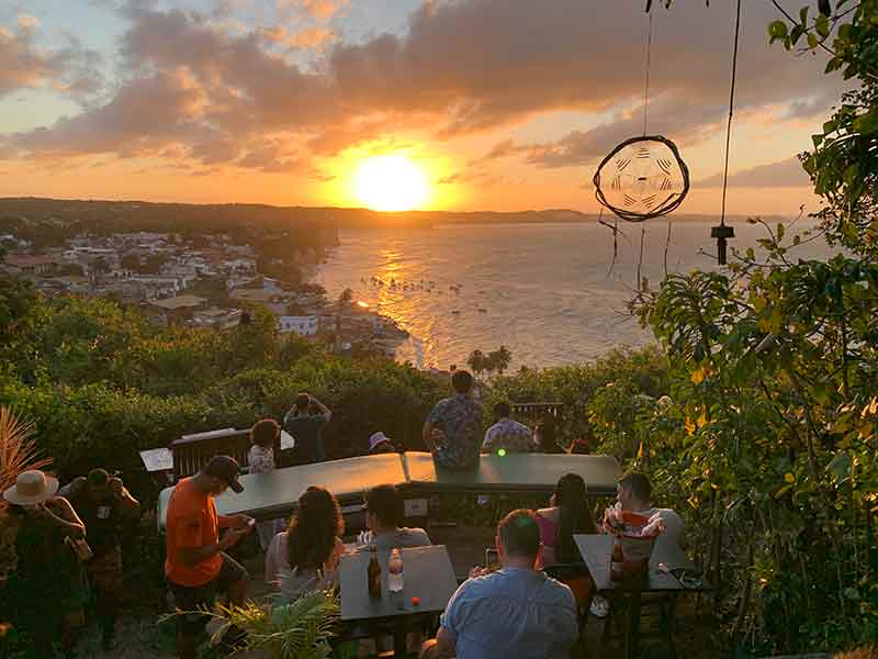 Pessoas veem o pôr do sol na Praia de Pipa no Mirante Sunset Bar