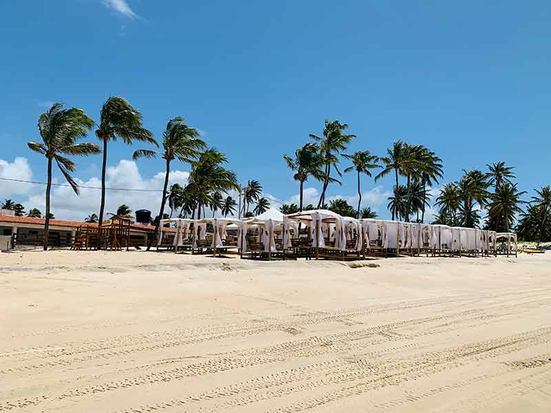 Beach club com tecidos brancos nas areias de Perobas, RN, em dia de céu azul