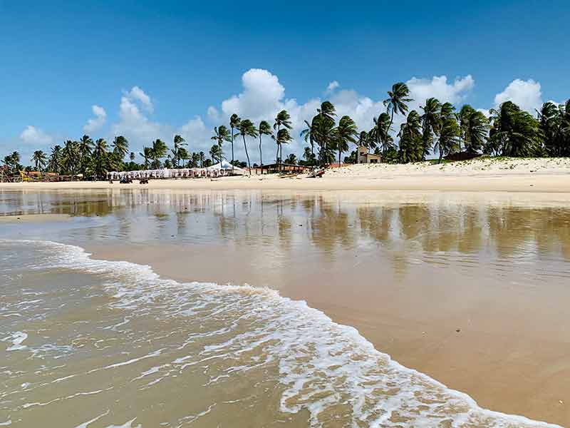 Vista de Perobas a partir do mar vazia com beach club na areia em dia de céu azul