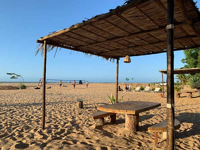 Mesa vazia ao lado e pessoas à frente praticam esporte na Ponta do Santo Cristo, em São Miguel do Gostoso