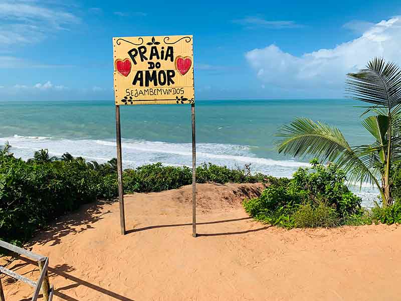 Placa da Praia do Amor com mar ao fundo em dia de céu azul