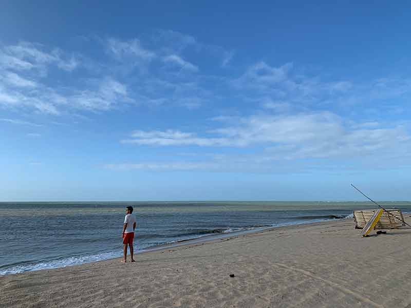 Homem em pé observa o mar na Praia do Cardeiro em São Miguel do Gostoso