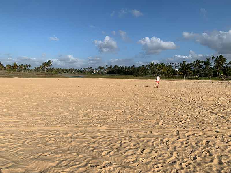 Homem anda em extensa faixa de areia em praia de São Miguel do Gostoso