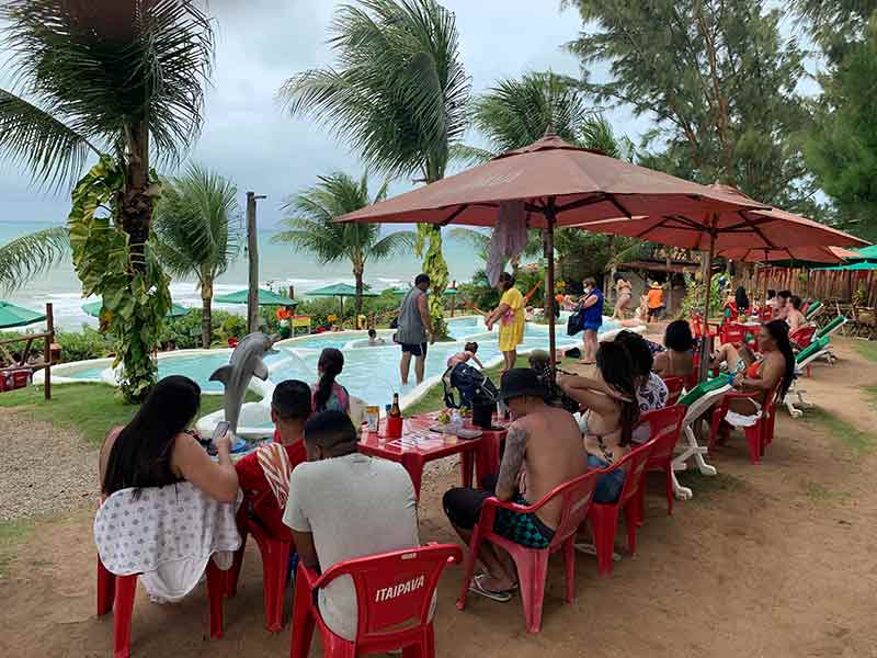 Restaurante Amô, na Praia de Pipa, com pessoas sentadas em mesas de plástico e piscina