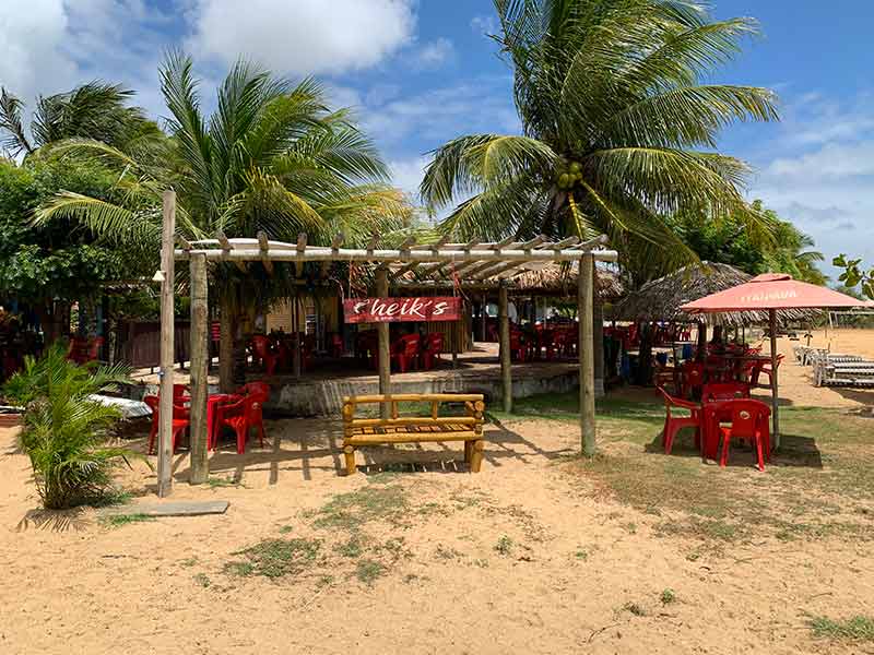 Barraca de praia Sheik's com mesas na areia na praia do Cardeiro