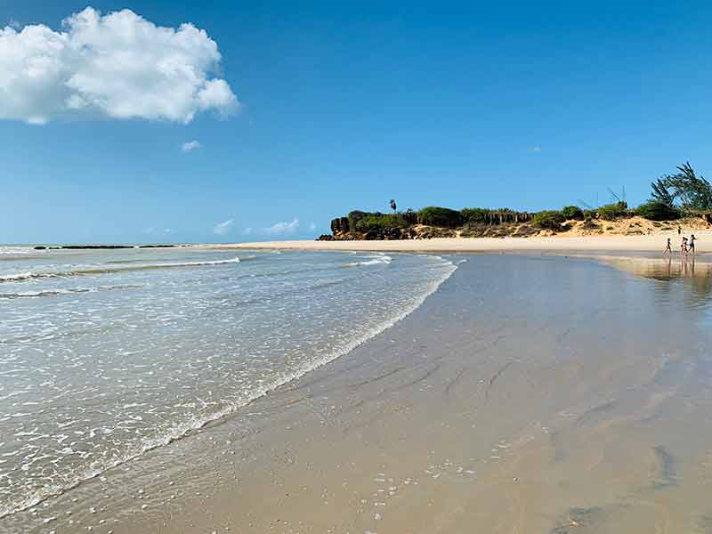 Mar vazio com pessoas caminhando na areia em Tourinhos, no Rio Grande do Norte
