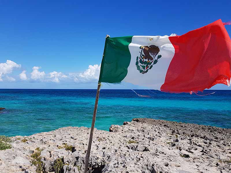 Bandeira do México em frente ao mar do Caribe em Cozumel