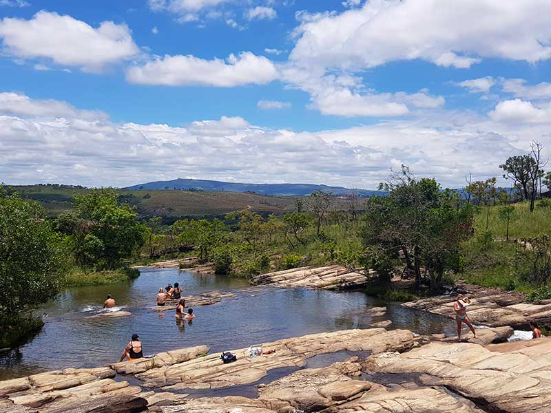 Banhistas em cachoeira com vista pras montanhas em Carrancas