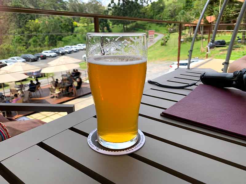 Chopp da Cervejaria 3 Orelhas, em Gonçalves, em cima de mesa de madeira em dia de sol