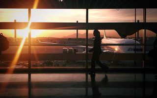 Mulher caminha em saguão do aeroporto do Galeão em pôr do sol