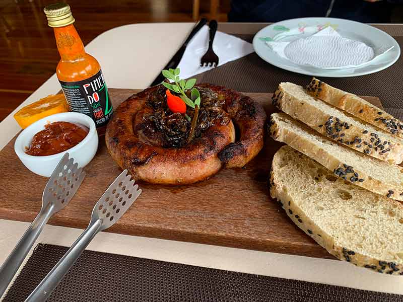 Linguiça com cebola caramelizada, geleia de maracujá e pães do restaurante Sauá