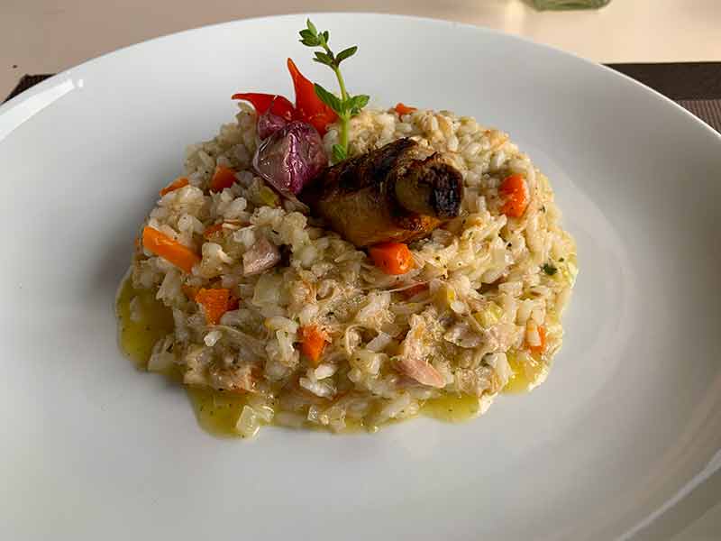 Prato branco com Risoto de galinhada com cenouras e frango do restaurante Sauá