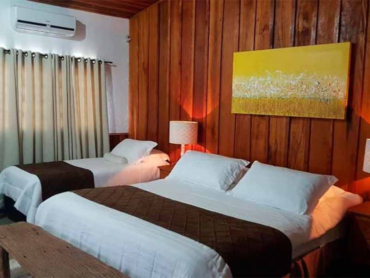 Quarto do Ladiv'ttá Spa & Hotel, dica entre os hotéis de Atibaia, com cama de casal e duas camas de solteiro e parede de madeira