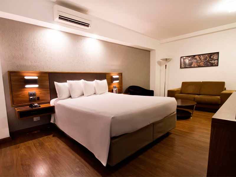 Quarto do Deville Hotel, dica de onde ficar em Curitiba, com cama de casal e piso de madeira
