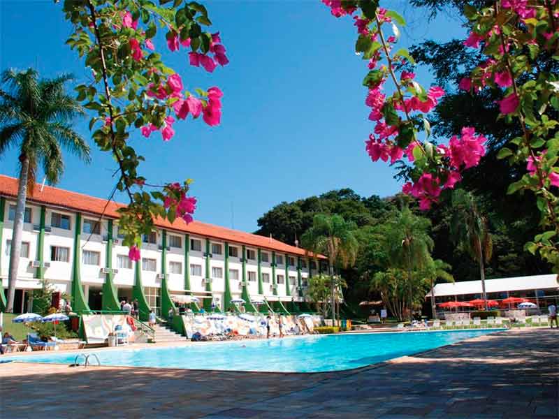 Piscina do Eldorado Eco Resort com flores acima da imagem em árvore e casarão à frente