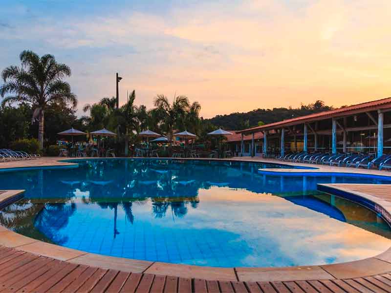 Final do dia na piscina do Hotel Fazenda Hípica Atibaia com cadeiras e guarda-sóis