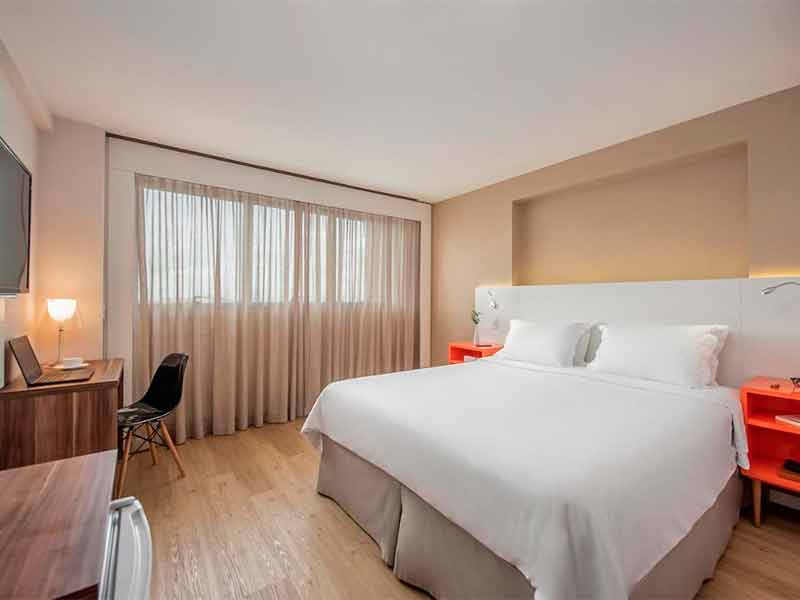 Quarto do Intercity Centro Cívico com cama de casal, TV, cortina e abajur