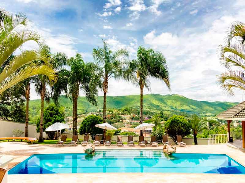 Piscina vazia do Vila Verde com árvores, espreguiçadeiras e guarda-sóis