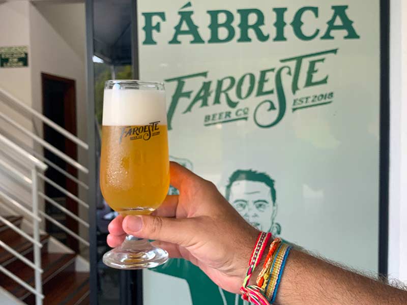Homem segura copo com chopp da cervejaria Faroeste, em Itajaí
