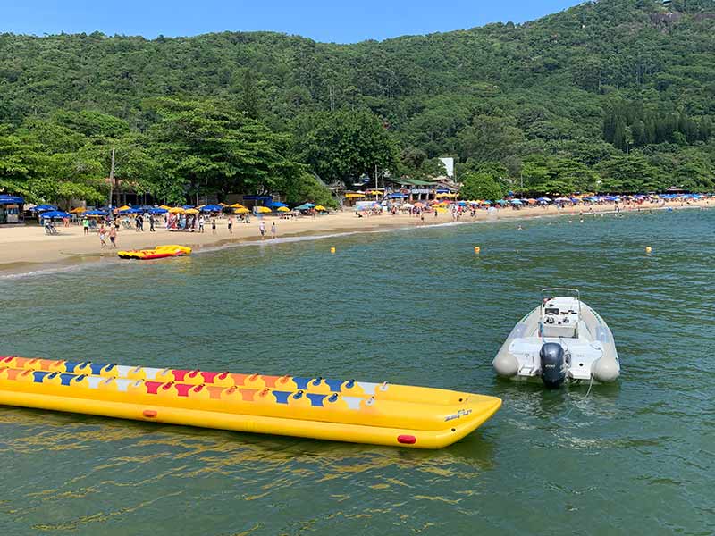 Mar esverdeado com guarda-sóis na areia na praia de Laranjeiras