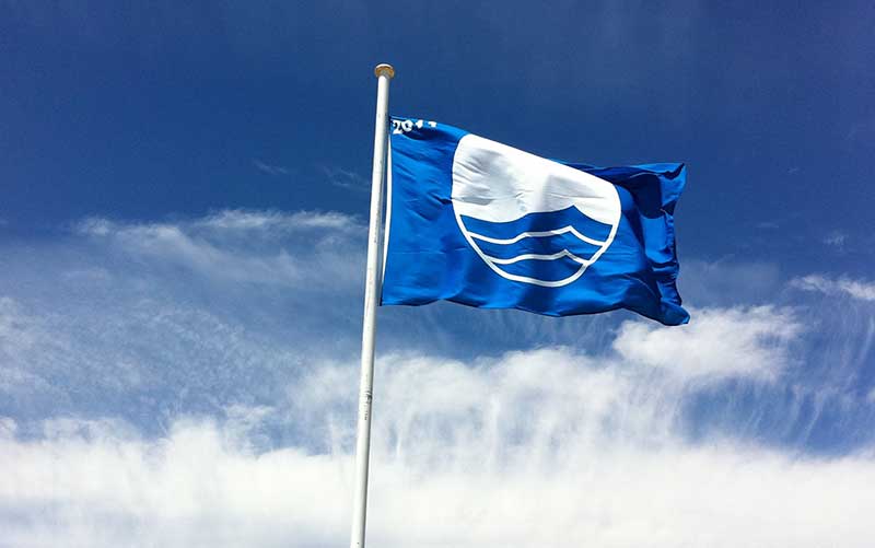 Bandeira azul hasteada em céu azul com algumas nuvens