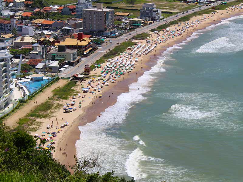 Vista de cima da Praia dos Amores, em Balneário Camboriú, com guarda-sóis na areia