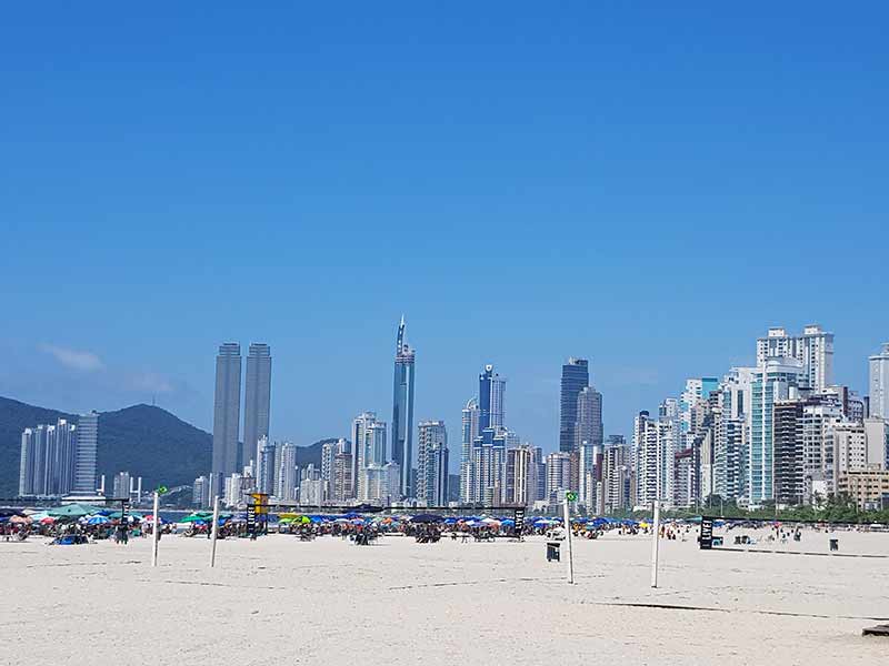 Quando ir pra Balneário Camboriú: Céu azul e prédios altos vistos da areia da Praia Central