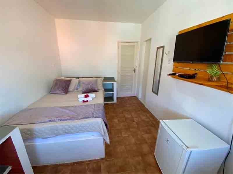 Quarto simples da pousada Barra Lounge com cama de casal e TV