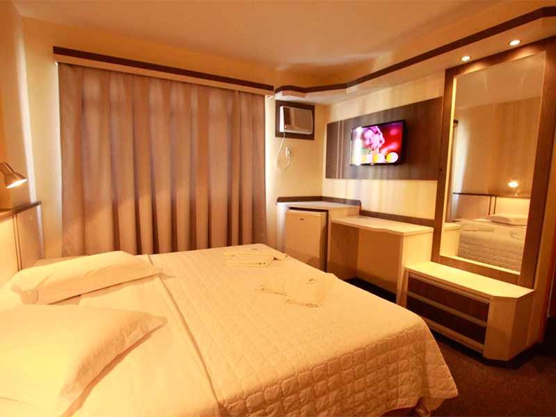 Quarto do Hotel Blumenau, dica de onde ficar em Balneário Camboriú, com cama de casal, TV e espelho