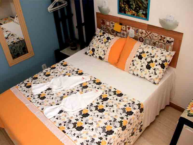 Quartol do Camping e Chalés Beira Mar com cama de casal em tons amarelos e laranjas