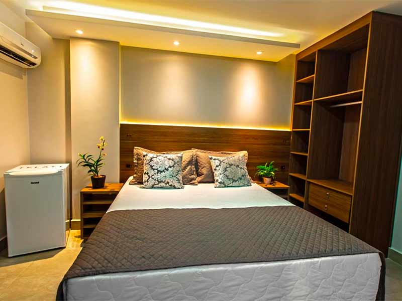 Quarto do Flat Concept com cama de casal e móveis de madeira