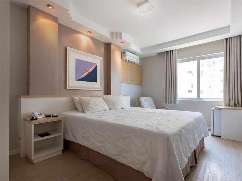 Quarto do Miramar com decoração clara, quadro na parede, ar-condicionado e cama de casal