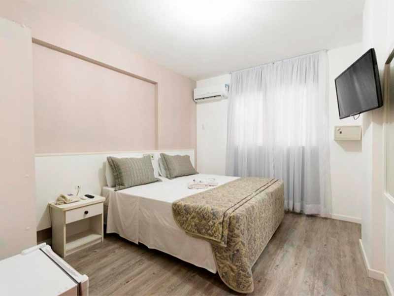 Quarto do Hotel Negrini com cama de casal e decoração clara