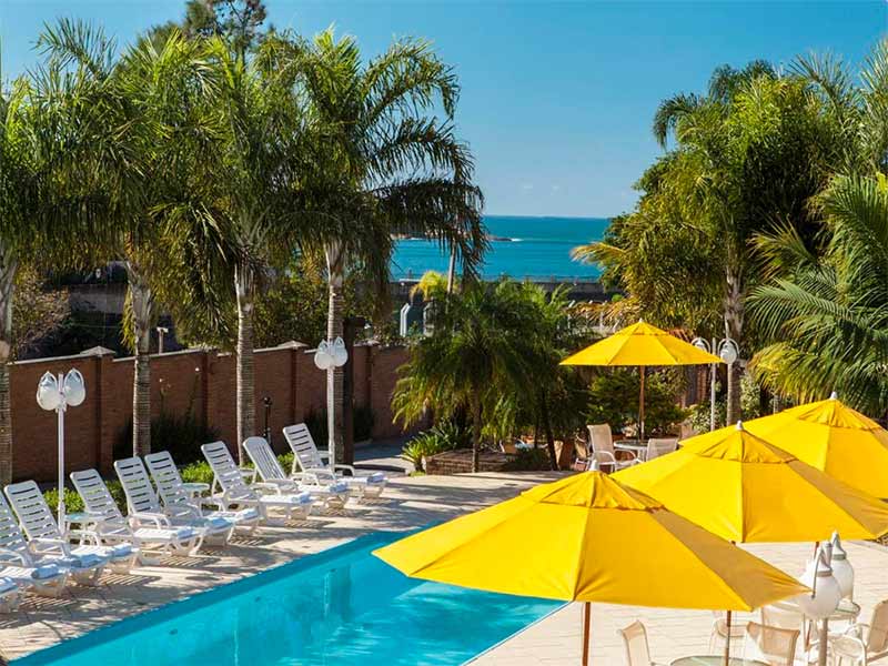 Espreguiçadeiras vazias na piscina da Ponta do Lobo, dica de onde ficar em Balneário Camboriú, com mar à frente