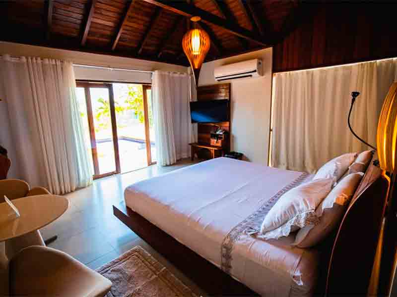 Quarto da Rangai com janela aberta, cama de casal, TV e ar-condicionado