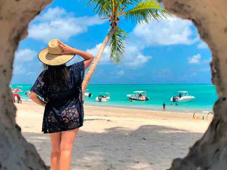 Pousada na Praia de Antunes: Mulher de preto posa de costas segurando chapéu olhando para a praia