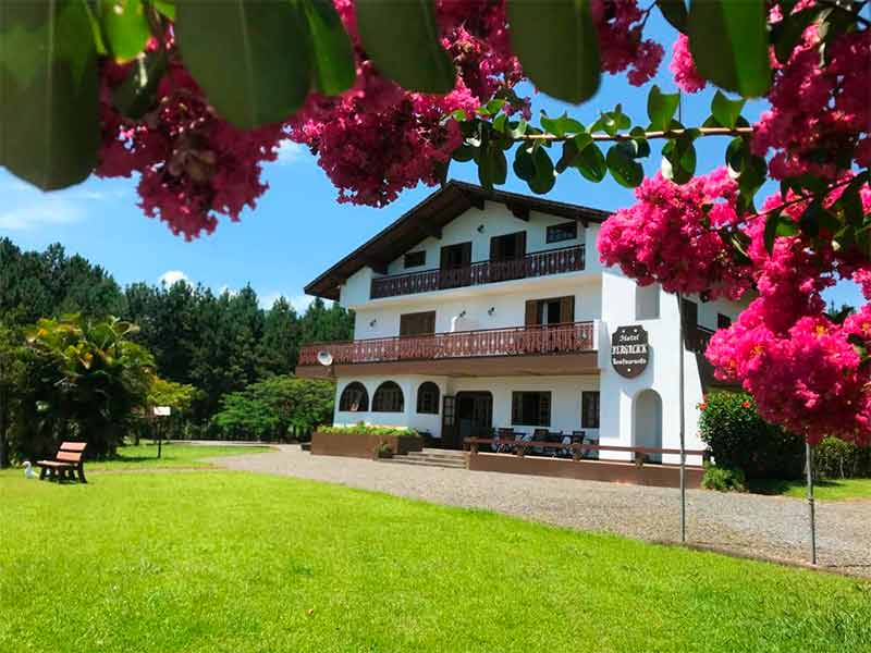 Área externa do hotel Bergblick com gramado verde e flores